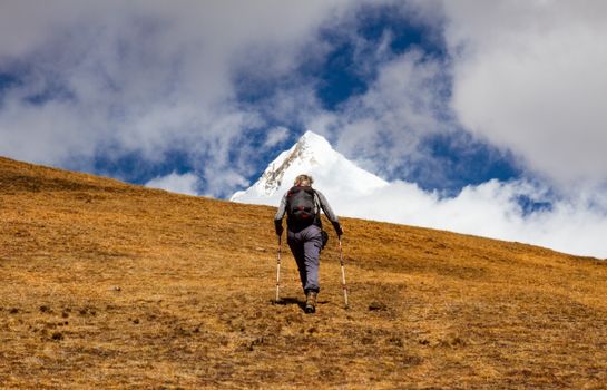 A lone hiker trekking up a mountain with snow-capped peaks, ideal for adventure and travel themes.