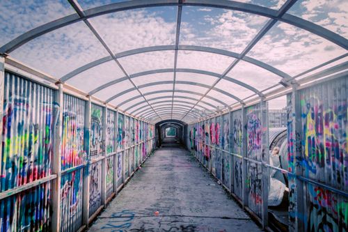 Free Colorful graffiti decorates an urban pedestrian tunnel under a clear blue sky. Stock Photo