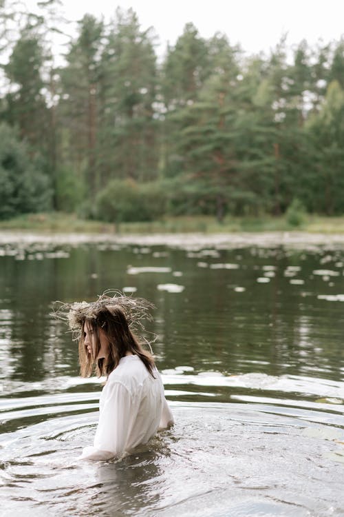 A Person in White Long Sleeves Soaking on a Pond while Looking Afar