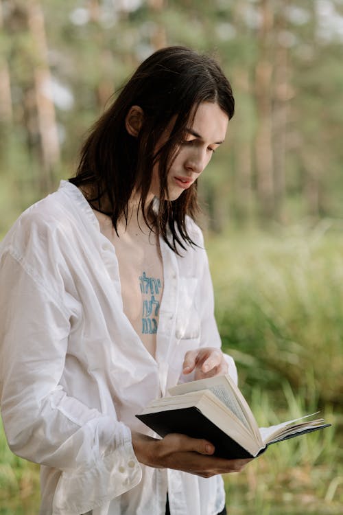 Женщина в белой рубашке с длинным рукавом читает книгу