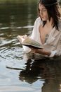 Woman in White Robe Reading Book on Water