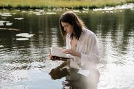 Woman in White Long Sleeve Shirt Reading Book on Water