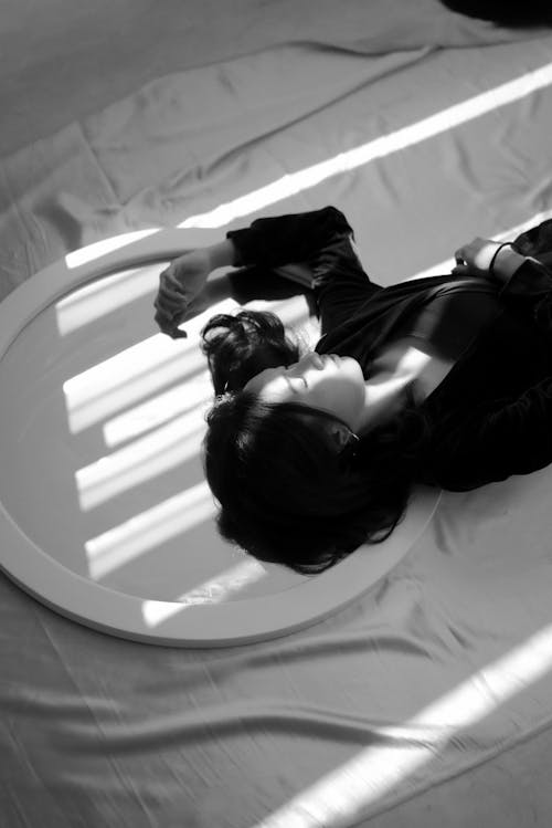 Grayscale Photography of a Woman Lying on Bed
