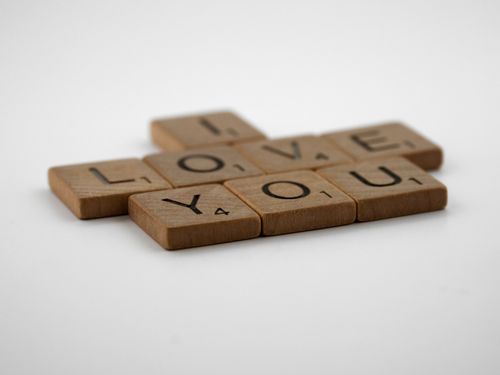 Free Creative arrangement of scrabble tiles spelling 'I Love You' on a white surface, perfect for romantic messages. Stock Photo