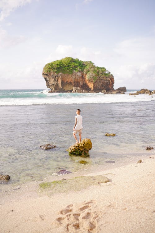 A Man Standing on a Rock at the Beach