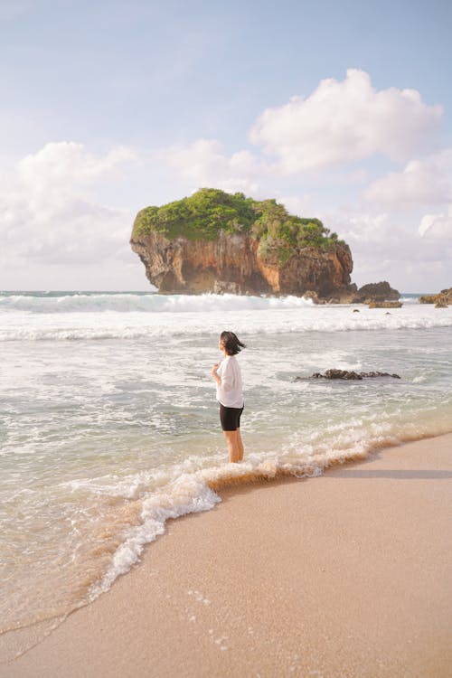 Free Side View Shot of a Woman Standing on the Shore of the Sea Stock Photo