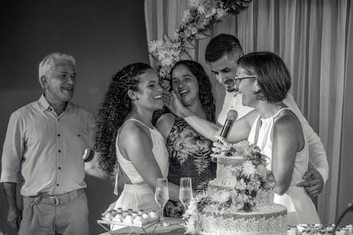 Black and white of group of cheerful people on wedding party in restaurant with cake and decorations