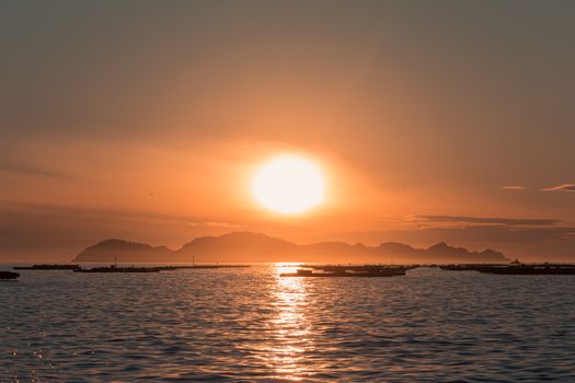 Breathtaking sunset casting golden light over a tranquil sea and distant island.