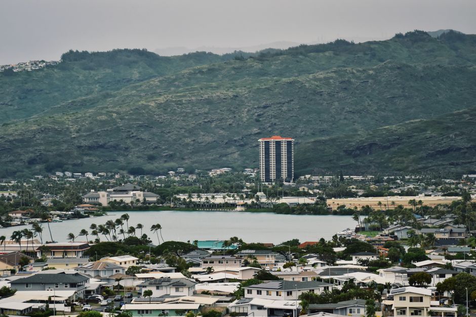 Photo by Annalicia Lima Aerial view of a cityscape with a lake and mountainous backdrop.