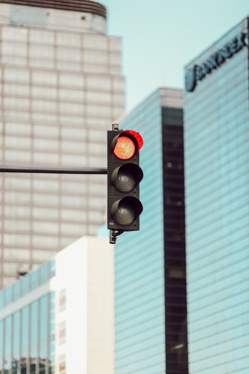 Free Vertical shot of a red traffic light against high-rise buildings in Jakarta cityscape. Stock Photo