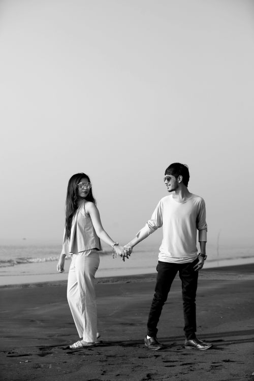 Free Romantic grayscale image of a couple holding hands on a Surat beach in India. Stock Photo