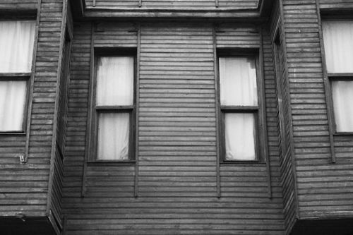 Free A grayscale photograph of a vintage wooden facade featuring classic window designs. Stock Photo