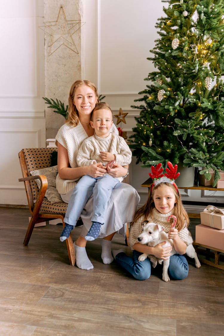 Photo Of Mother And Children Sitting Near A Christmas Tree With Their Dog