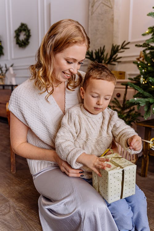 Free Boy Sitting on a Woman's Lap Holding a Gift Stock Photo