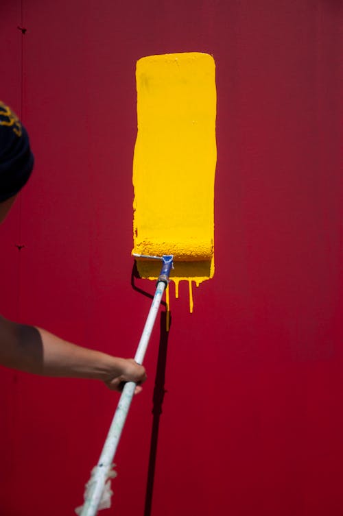 Free Anonymous painter with yellow roller painting Stock Photo