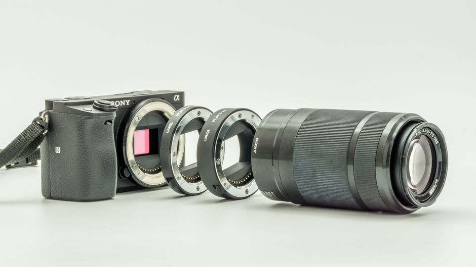 Exploded camera view showcasing adapters and lens parts on white background.