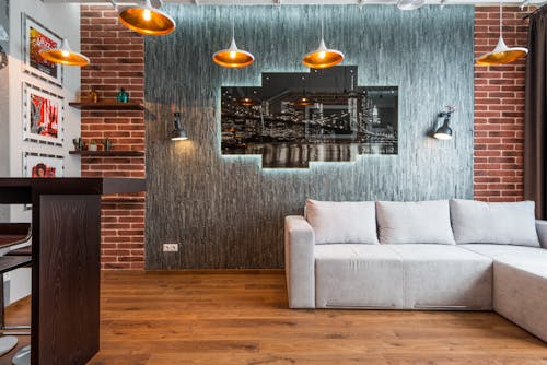 Interior of modern lounge zone with soft couch near creative brick wall with illuminated picture
