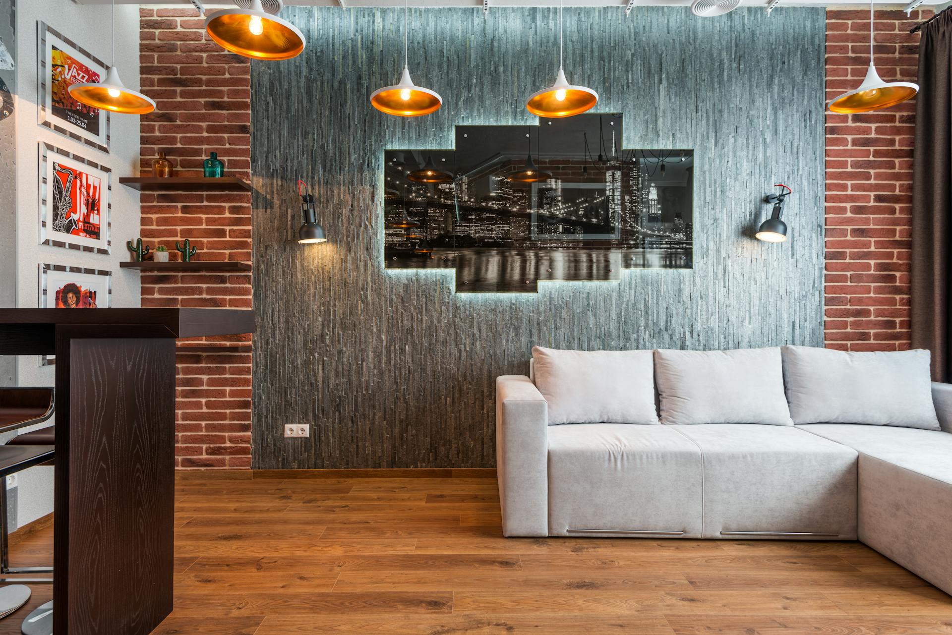 Interior of modern lounge zone with soft couch near creative brick wall with illuminated picture