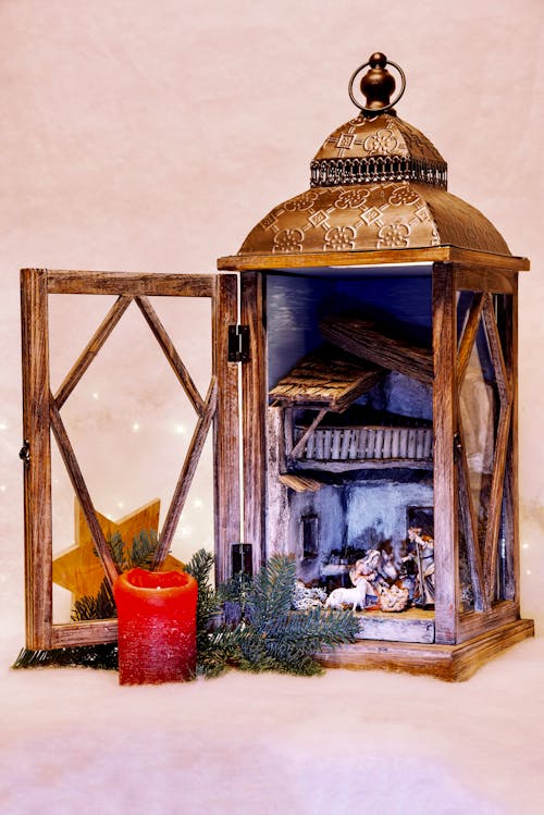 Retro wooden opened candle lantern with decorative elements placed on white surface with candle and coniferous branch during Christmas holiday