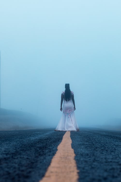 Free Woman in White Dress Standing on The Lane Of A Road Stock Photo