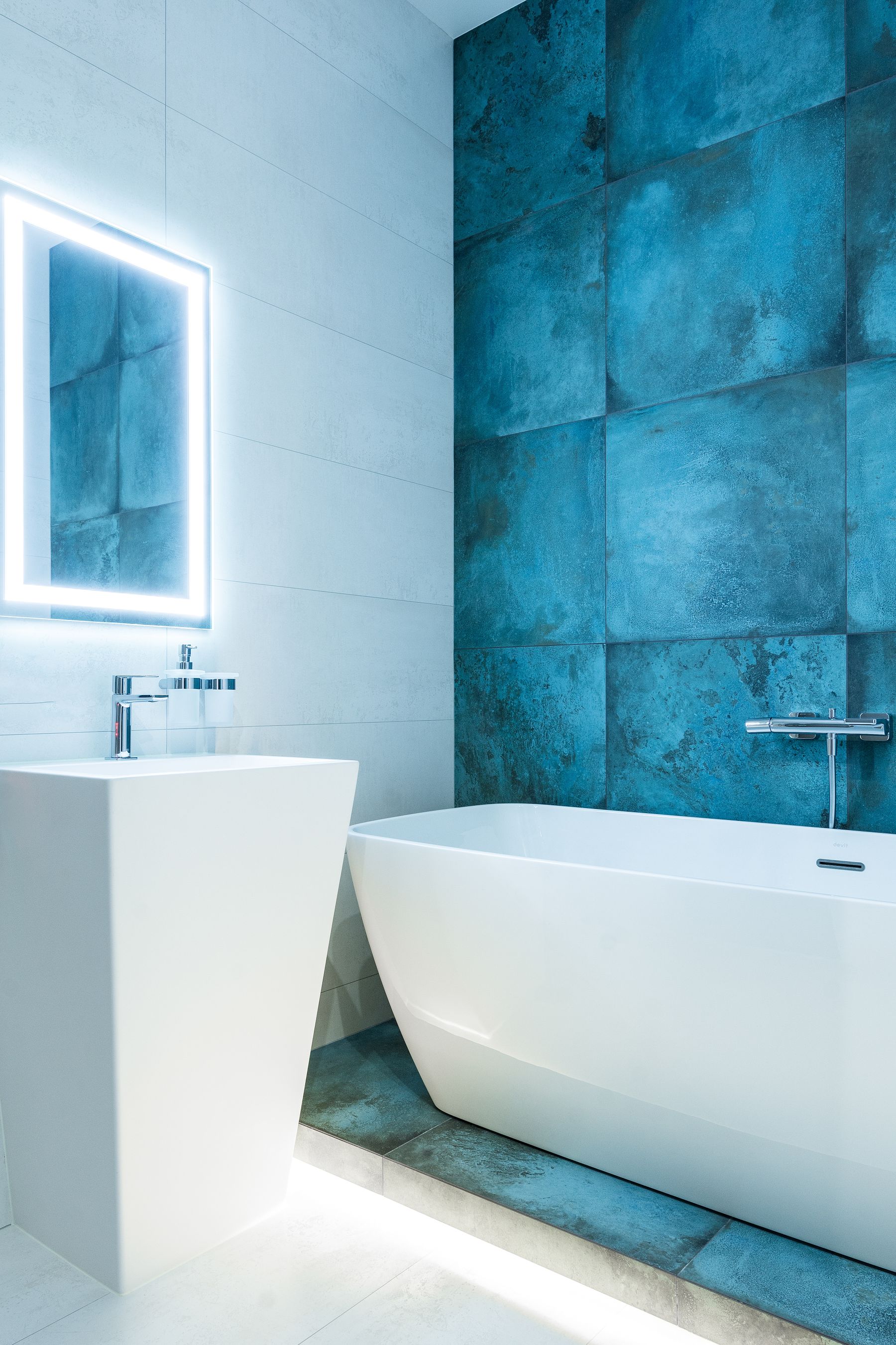 White room with a defined blue accent wall behind a freestanding bath