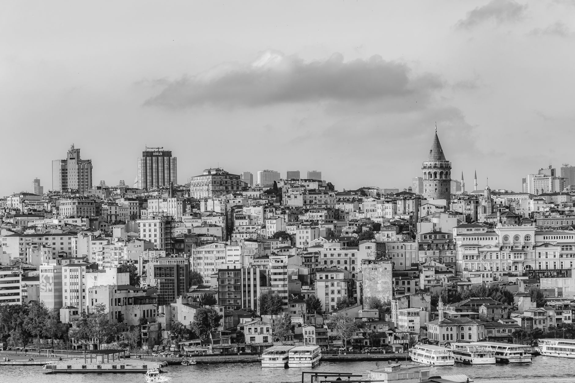 A monochrome cityscape of İstanbul featuring high-rise buildings and the iconic Galata Tower.