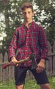 Serious man with axe standing in rural garden