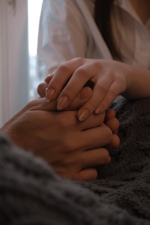 Crop unrecognizable couple holding hands together