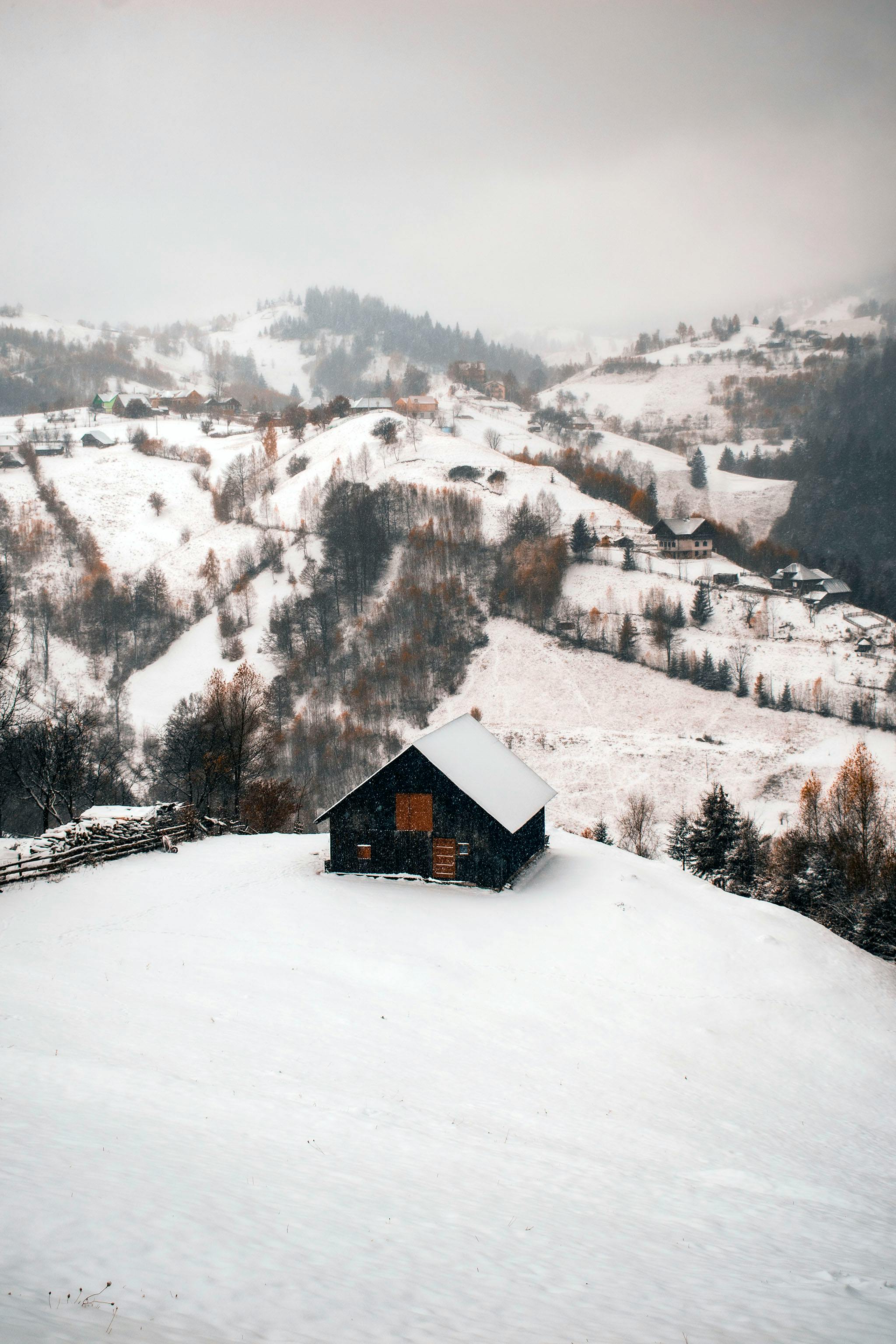 Serene winter landscape featuring a secluded cabin amidst snowy Romanian mountains.