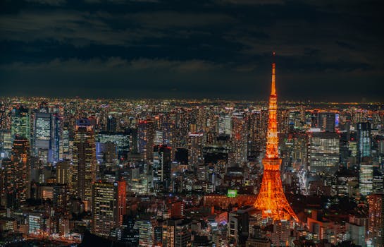 A stunning aerial night view of Tokyo featuring the illuminated Tokyo Tower and bustling cityscape.