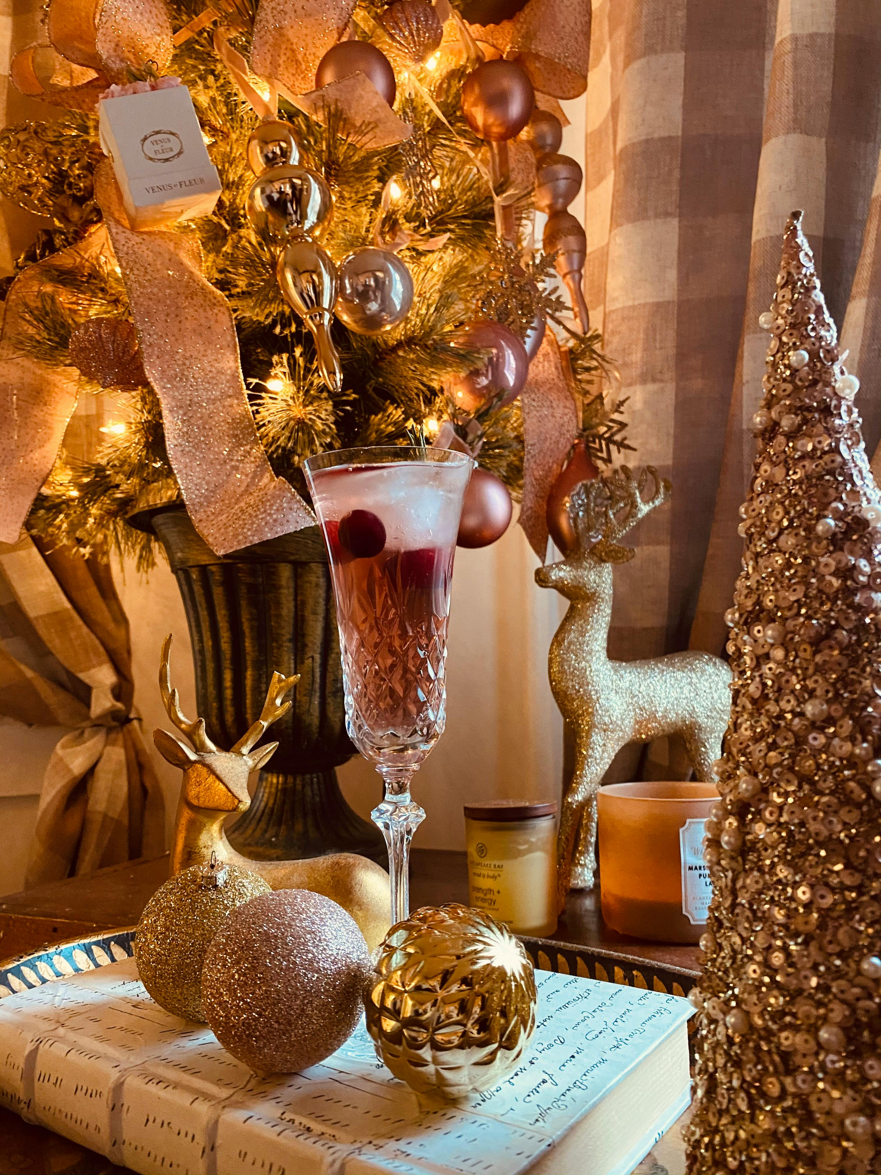 Festive holiday scene with Christmas ornaments, elegant glass of cocktail, and sparkling decorations