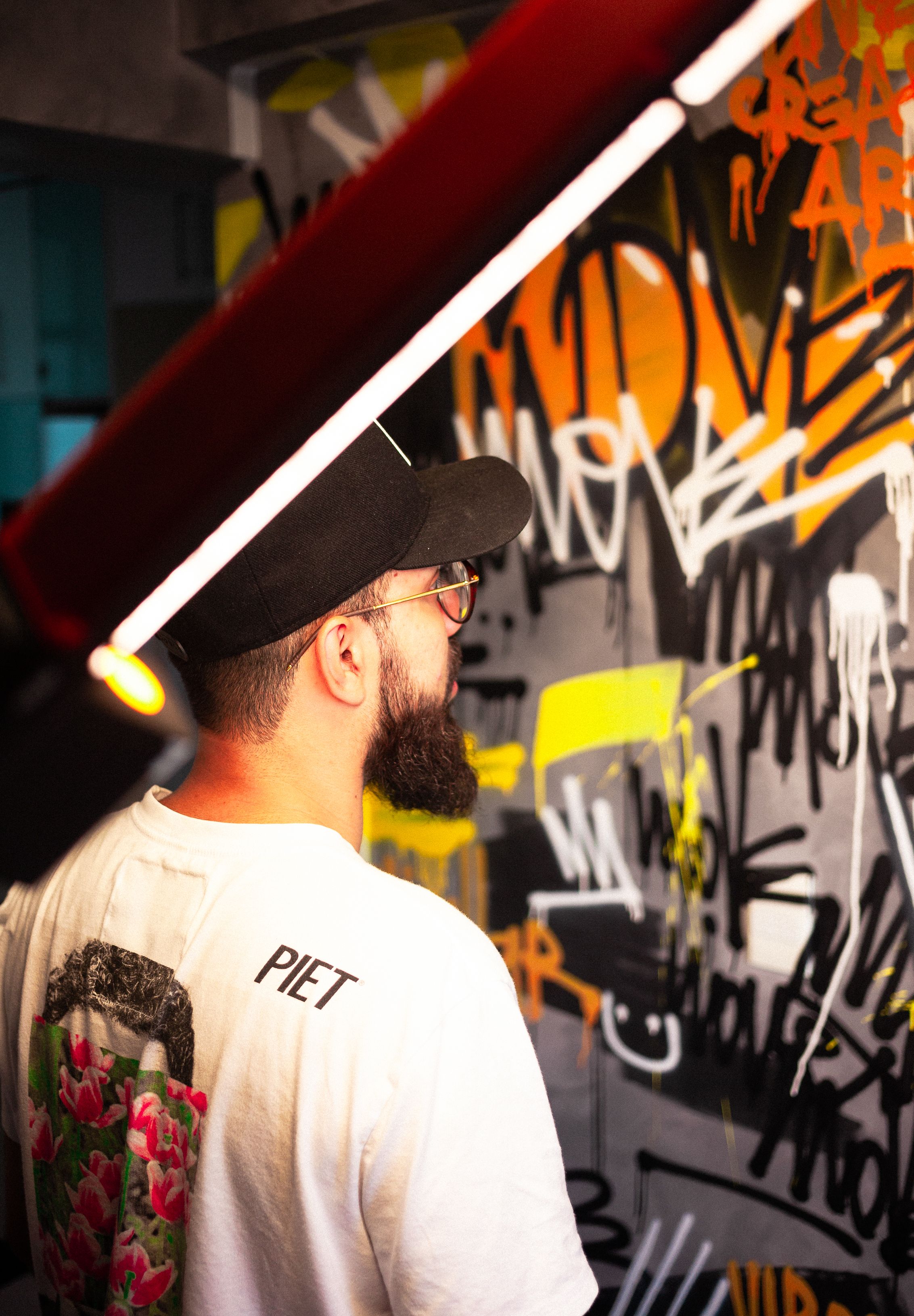 A modern artist with a beard working on an abstract graffiti mural in a vibrant urban setting.
