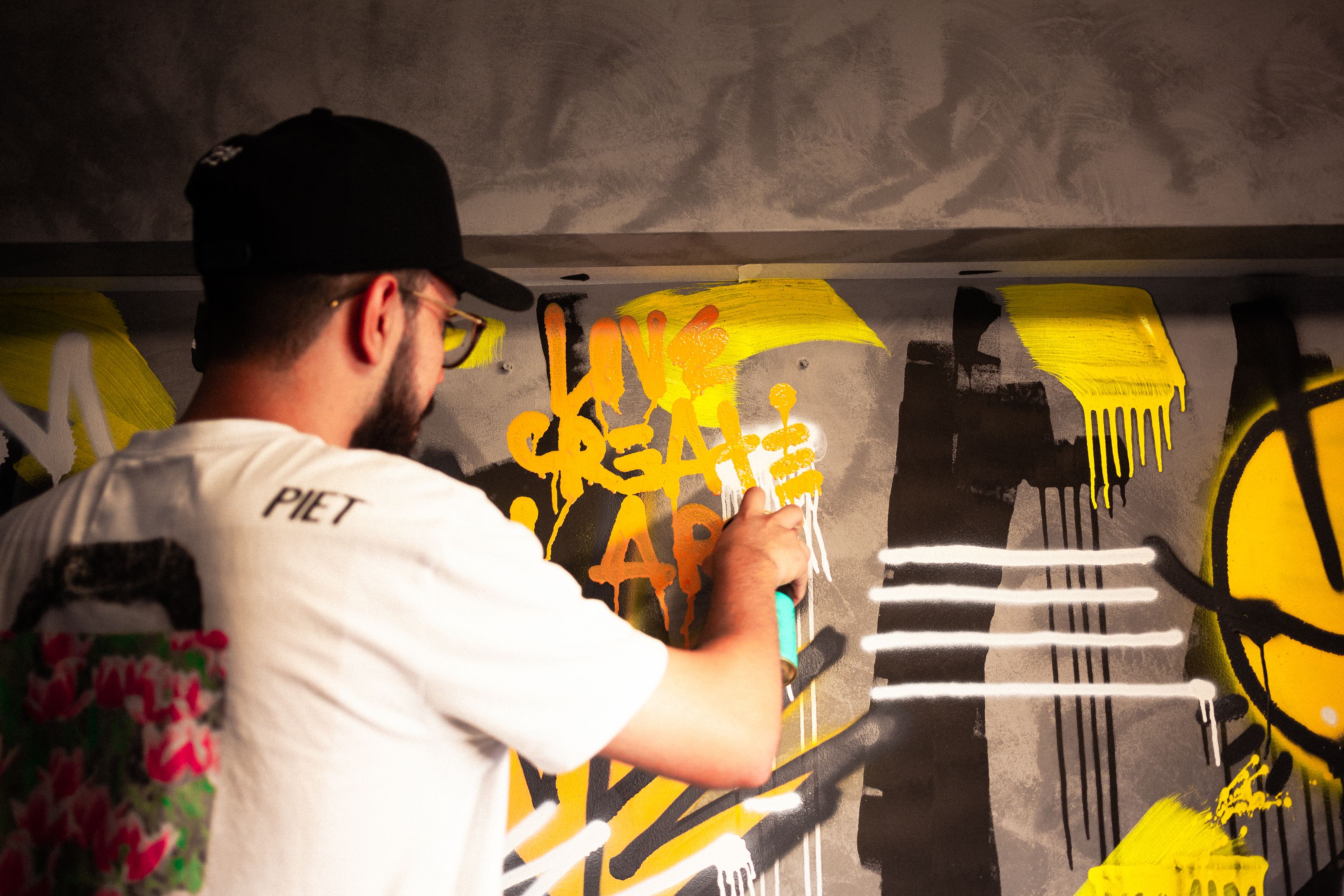 Artist spray painting colorful graffiti on a wall, emphasizing urban creativity.