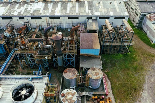 Drone view of industrial area with barrels for petroleum products and pipes connected with warehouses