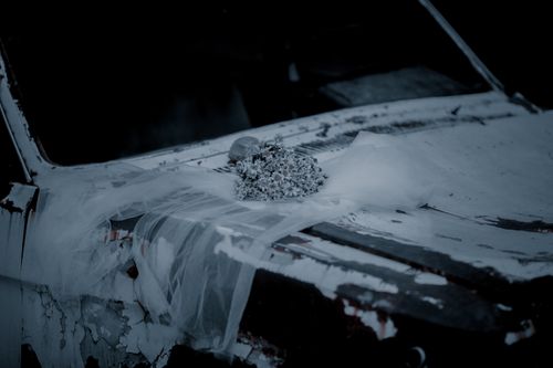 Free Silhouette of a wedding veil and flowers on the hood of an abandoned car in a moody grayscale scene. Stock Photo
