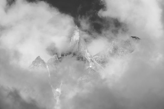 Stunning monochrome view of Swiss mountain peaks shrouded in clouds, capturing winter's majestic beauty.