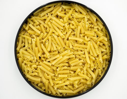 Free Close-up flat lay of assorted uncooked pasta in a circular bowl, perfect for culinary visuals. Stock Photo