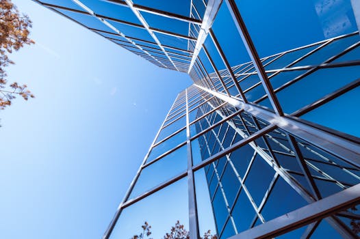Low angle view of a modern skyscraper with a reflective glass facade against a clear blue sky.