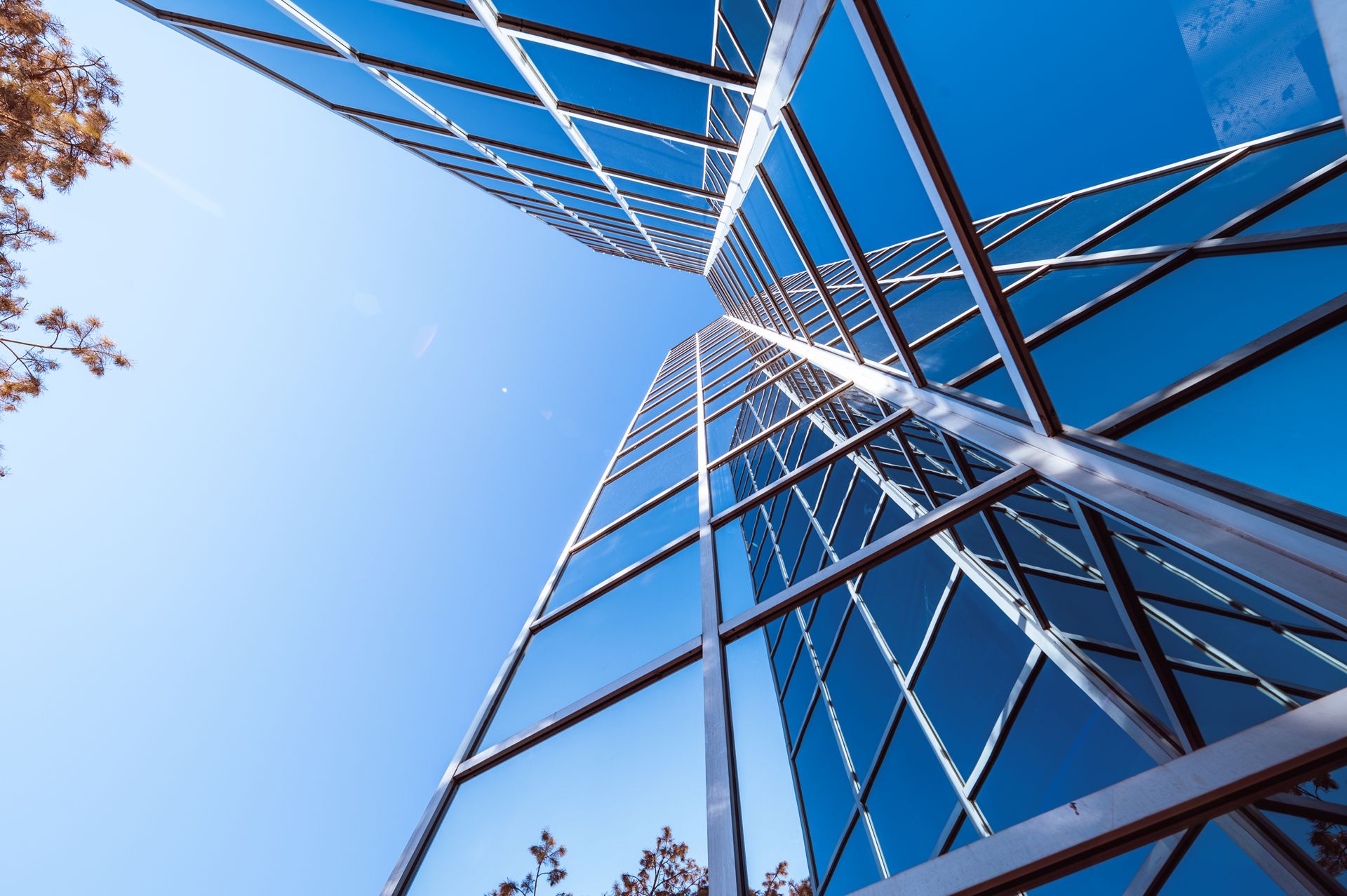 Low angle view of a modern skyscraper with a reflective glass facade against a clear blue sky.