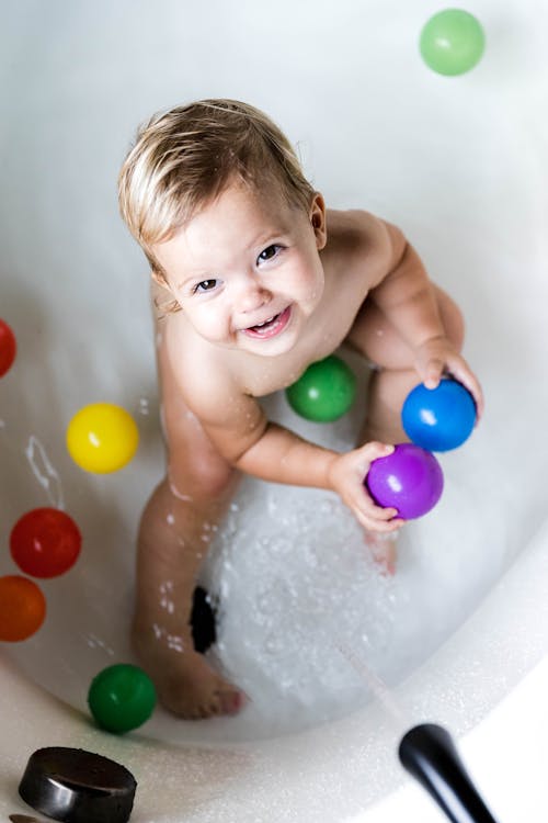 Smiling kid playing in bathtub with toys