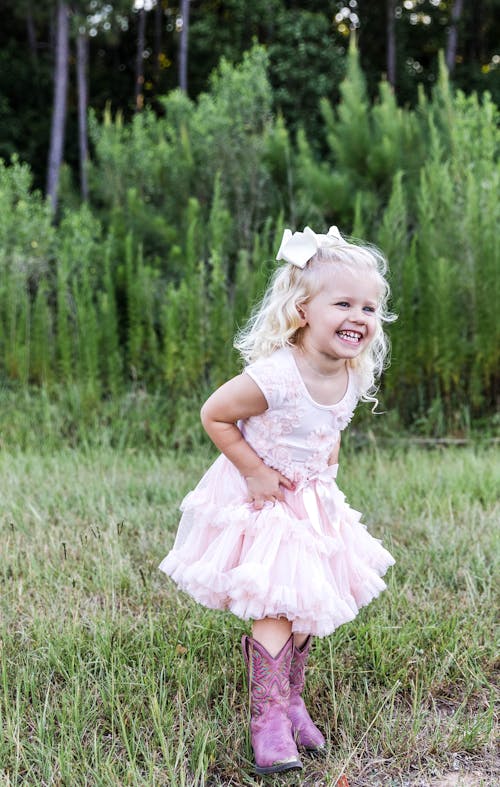 A Pretty Girl in White Dress Standing on a Grassy Field