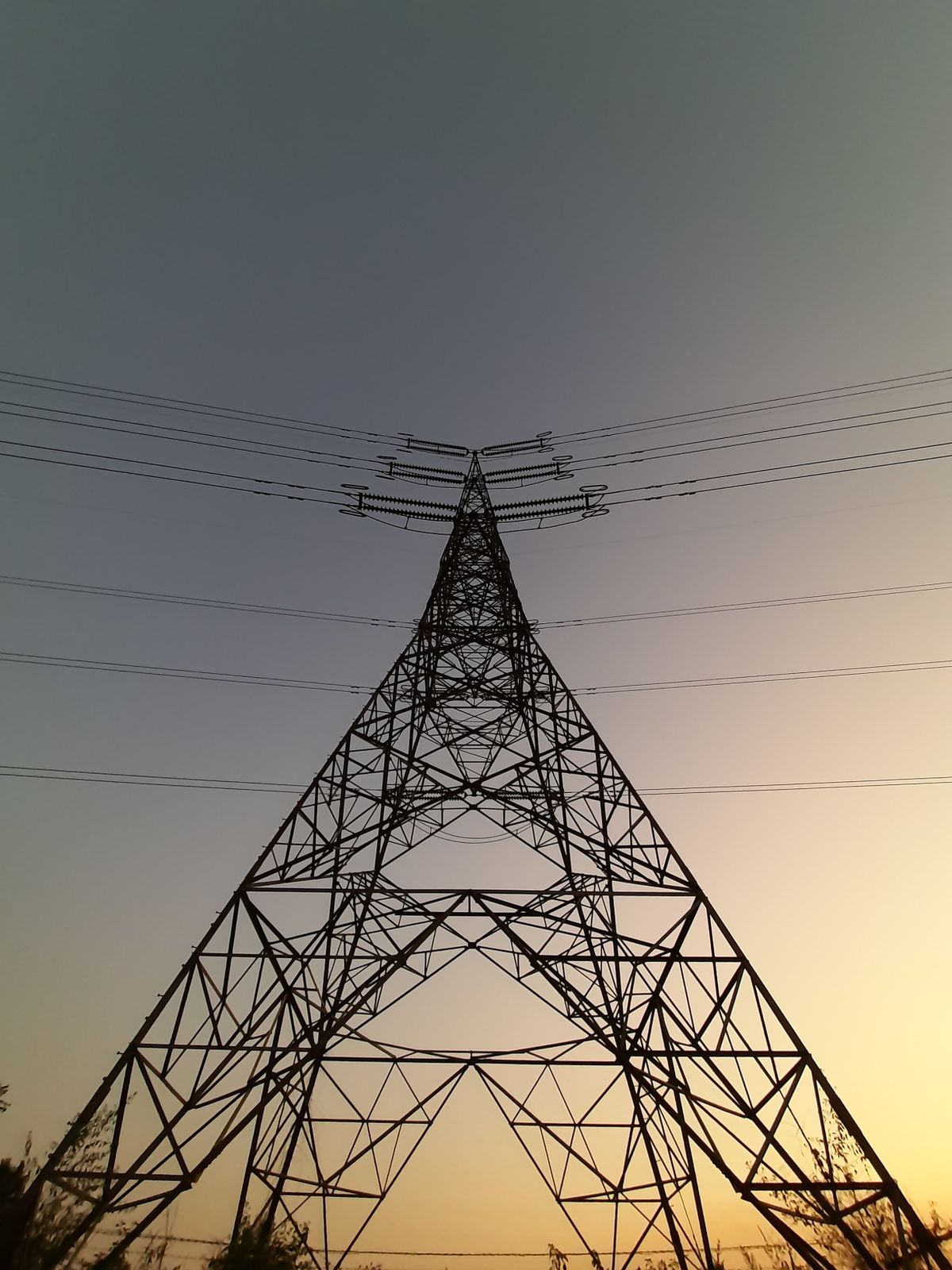 Extra-high-voltage transmission tower against a dusk sky