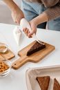 Person Decorating a Triangle Shaped Brown Cake
