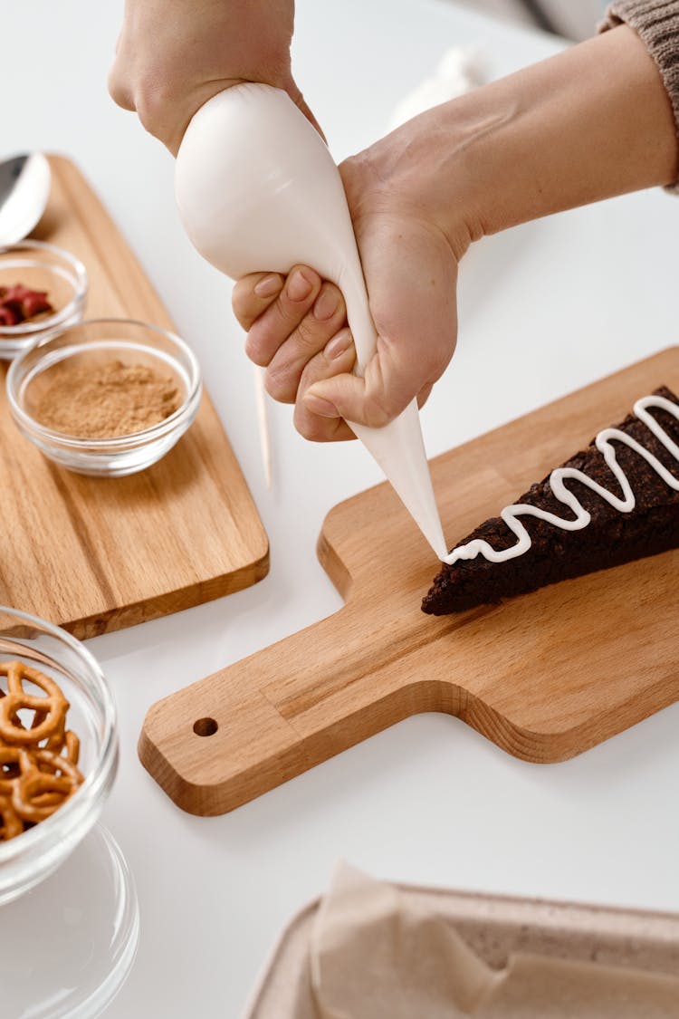 Person Decorating A Triangle Shaped Black Cookie