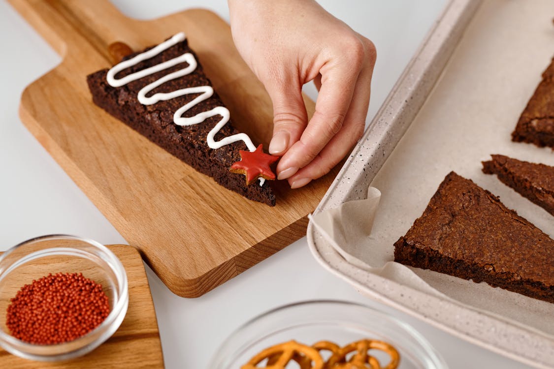 Person Decorating a Triangle Shaped Brown Cookie