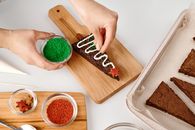Person Decorating a Triangle Shaped Brown Cookie