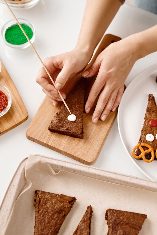 Free Hands decorating cake slices with icing on a wooden board, showcasing creative cake design. Stock Photo