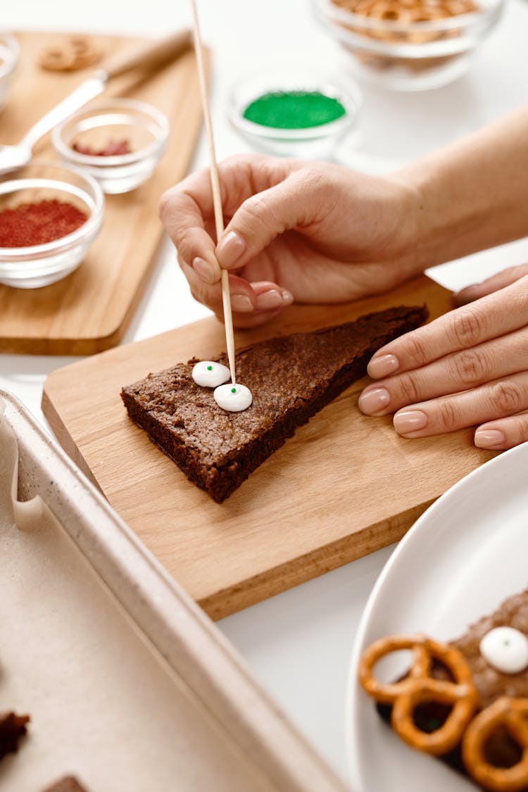 Person Decorating A Triangle Shaped Brown Cake