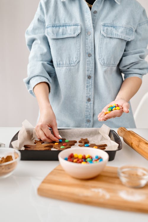 Person Decorating Brown Cookies With Chocolate Candies