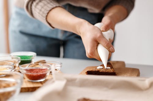 Person Decorating a Brown Cookie